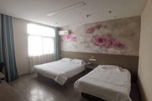 Une chambre d’hôtel avec deux lits, un bureau, une chaise, une fenêtre avec des rideaux et un mur orné d’une fresque florale.