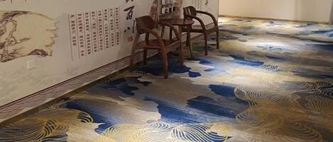 Una habitación con un diseño tradicional de piso asiático, una mesa de comedor con sillas y una pared con caligrafía.