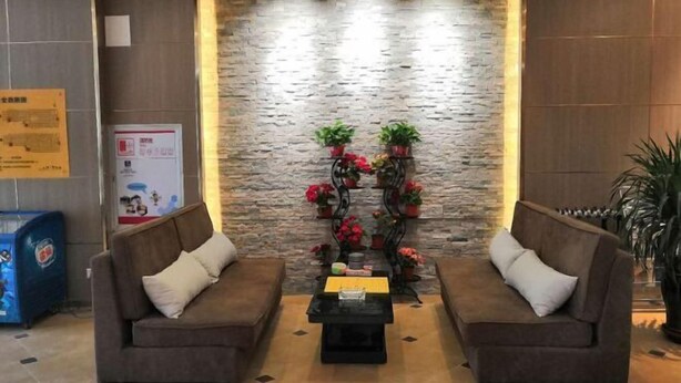 Un hall d’entrée avec deux canapés, une table basse et un arrangement floral décoratif placé contre un mur en pierre.