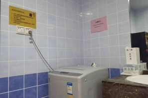 Ein Badezimmer mit Handtrockner, Waschbecken und einem Schild an der Wand.