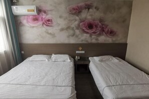 Une chambre d’hôtel avec deux lits simples, un climatiseur fixé au mur et une fresque murale à motifs floraux.