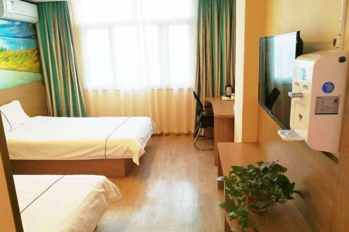 Une chambre d’hôtel avec deux lits, un bureau, une télévision et un distributeur d’eau.