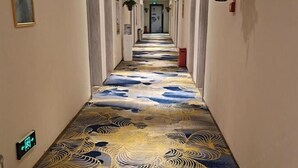 Un couloir avec un tapis à motifs et une poubelle rouge.