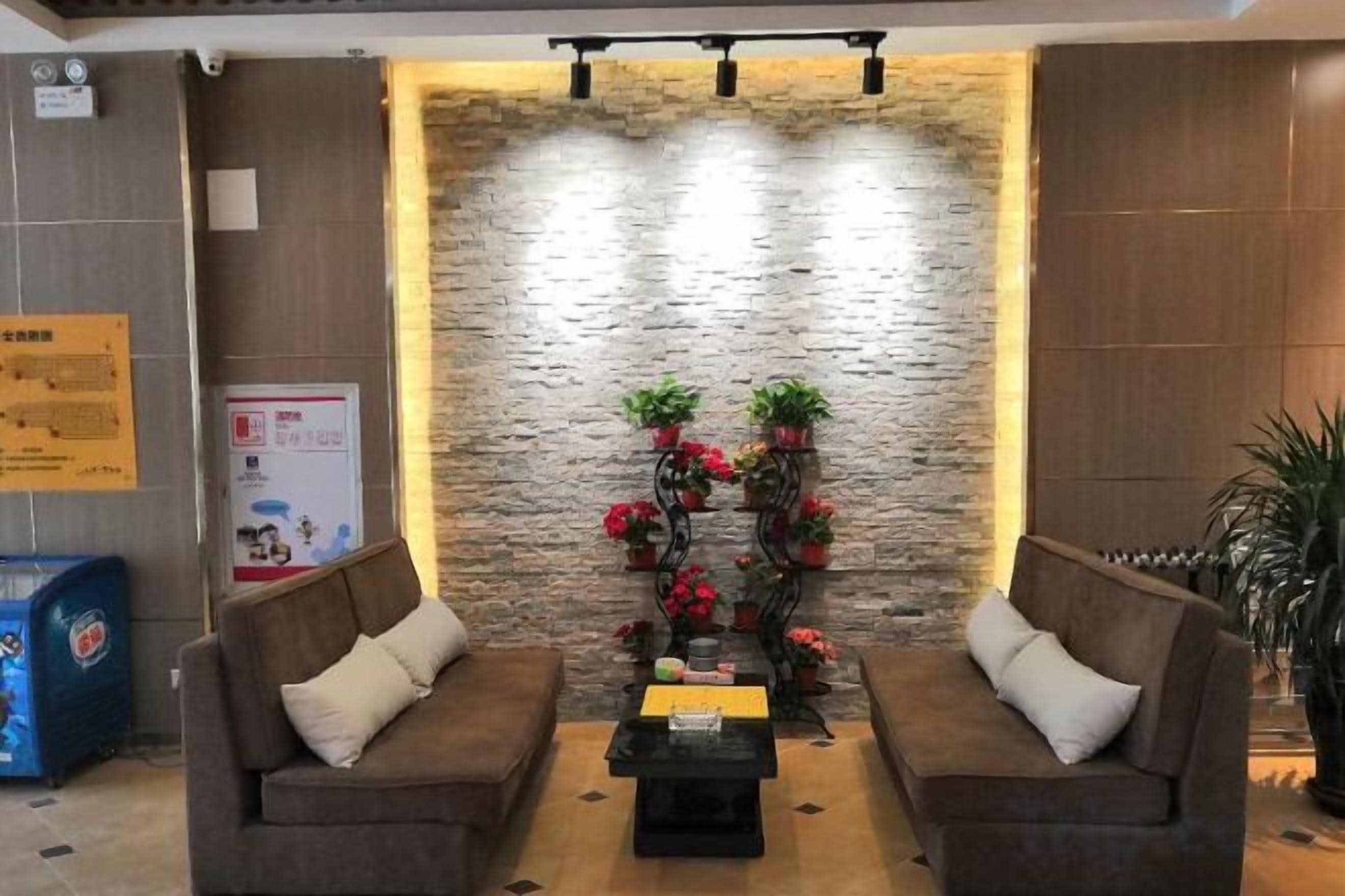 A lobby with two sofas, a coffee table, a stone wall, and a decorative plant arrangement.