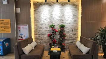 A lobby with two sofas, a coffee table, a stone wall, and a decorative plant arrangement.