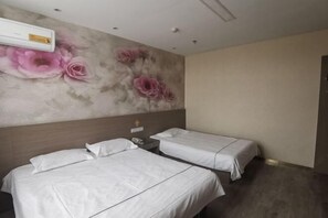 Une chambre d’hôtel avec deux lits, un climatiseur fixé au mur et une fresque murale à motifs floraux.
