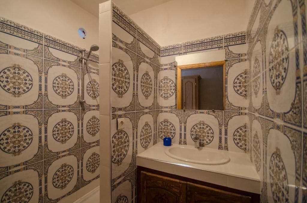 A bathroom with patterned tiles, a sink, and a mirror.