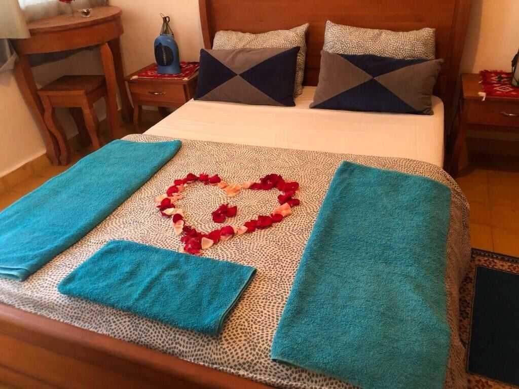 Uma cama bem arrumada com um arranjo floral em formato de coração e toalhas azuis.