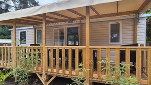 Une terrasse en bois dotée d’un espace abrité, d’une fenêtre et d’une porte.