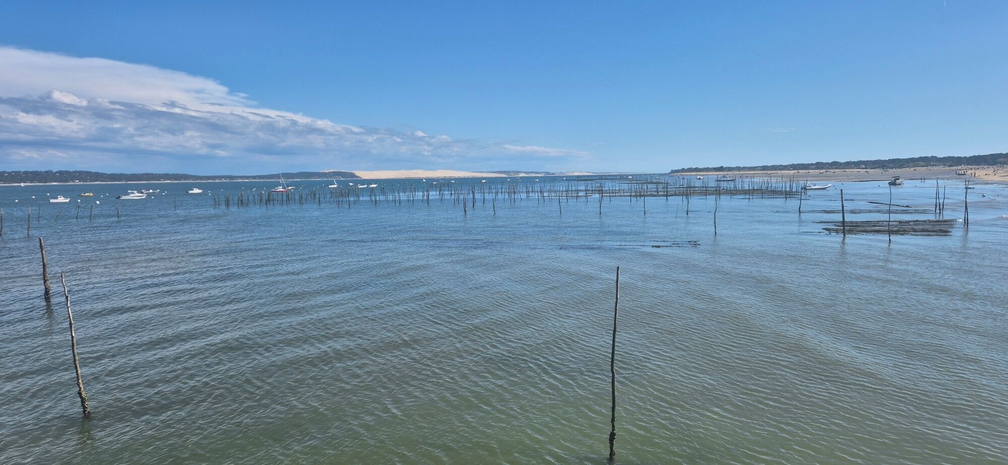 A coastal view with calm waters, boats, and a sandy beach.