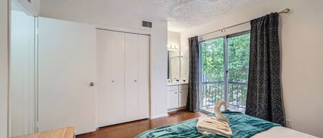 A bedroom with a bed, a desk, a ceiling fan, and a window with curtains.