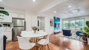 A modern kitchen with white cabinets, a stainless steel refrigerator, and a white dining table with four chairs. - 2B Getaway | Steps 2 Dtwn | Sleeps 6 | Pool + Prkg (Austin)