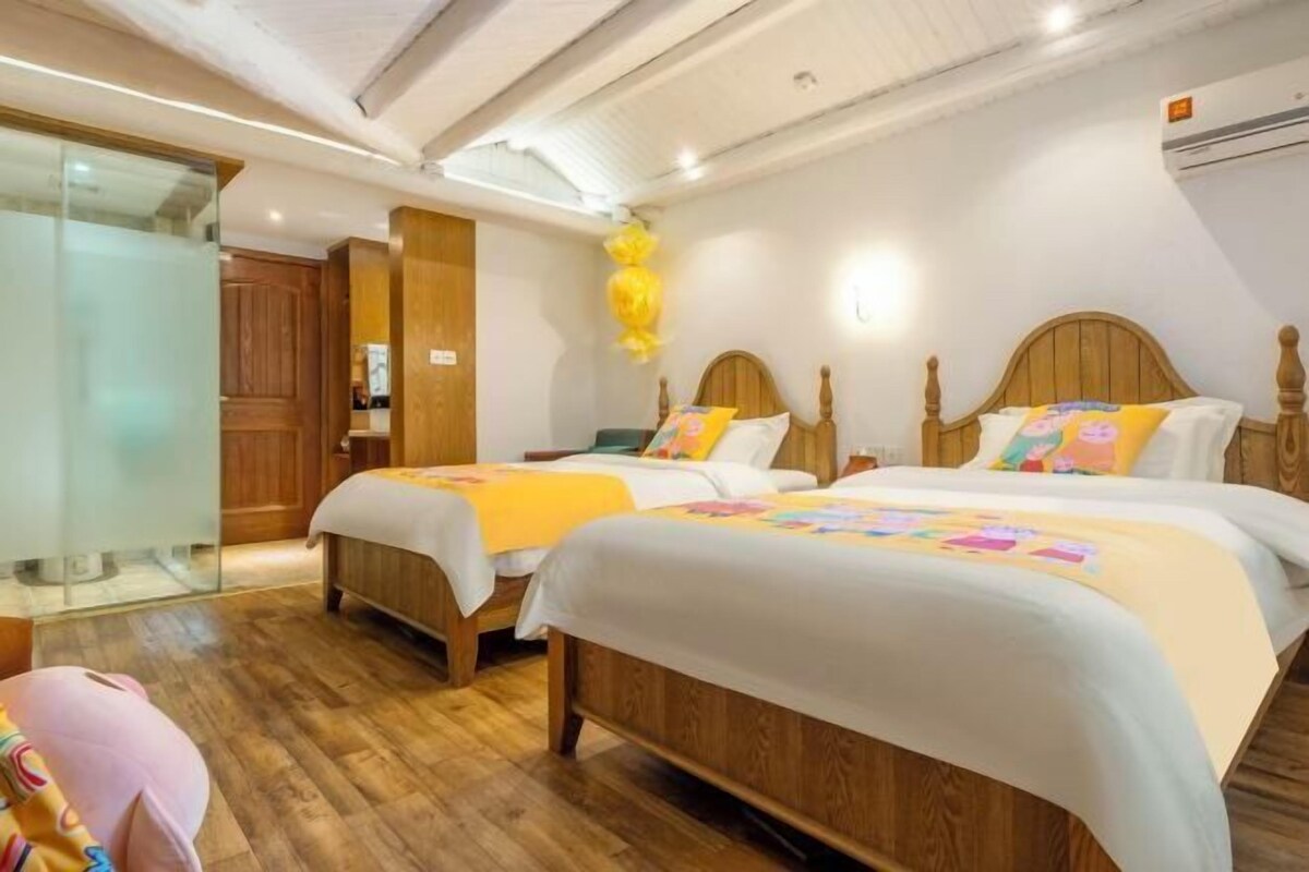 Une chambre d’hôtel avec deux lits en bois, une cloison en verre et un plancher en bois.
