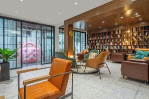 A modern interior with a seating area, a large bookshelf, and a view through glass doors.