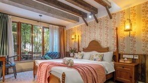 Une chambre à coucher avec un lit en bois, une table de chevet, une chaise et une fenêtre avec des rideaux.