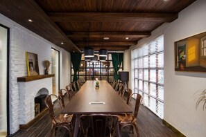 A long dining table with chairs, a fireplace, and a view through large windows.