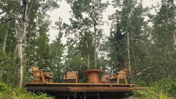 A wooden deck with outdoor furniture in a forested area.