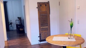 Een eetgedeelte met een ronde houten tafel, gele stoelen en een zwarte kruk.