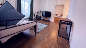 Een moderne slaapkamer met een bed, een televisie, een klein tafeltje en een radiator.