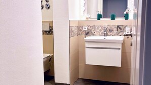 Een badkamer met een wit wastafel, spiegel en betegelde spatwand.