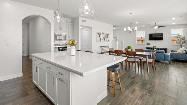 Una cocina moderna con armarios blancos, una isla grande e iluminación colgante.