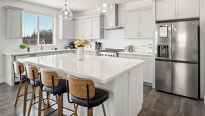 Una cocina moderna con una isla grande, electrodomésticos de acero inoxidable y vistas al exterior.