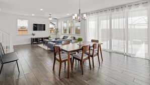 Una sala de estar moderna con comedor, ventanas grandes y ventilador de techo.