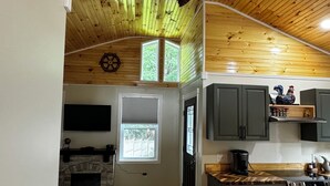 A kitchen with wooden ceiling, a fireplace, and a dining area with a table and chairs.