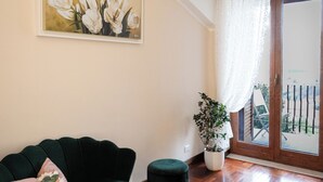 A room with a green sofa, a potted plant, a painting, and a wooden floor. - B&B La Piazzetta (Pianillo)