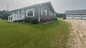 Een twee verdiepingen tellend huis met een veranda, een garage en een verzorgd gazon.