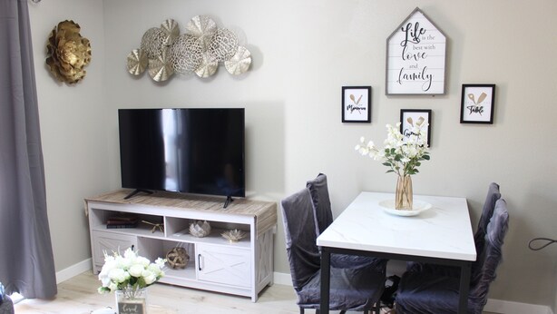 A living room with a TV, white console, and a dining table with chairs. - Brand new 2-bedroom in charming Santa Maria with WiFi, AC (Santa Maria)