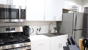 A modern kitchen with stainless steel appliances, white cabinets, and a black countertop. - Brand new 2-bedroom in charming Santa Maria with WiFi, AC (Santa Maria)