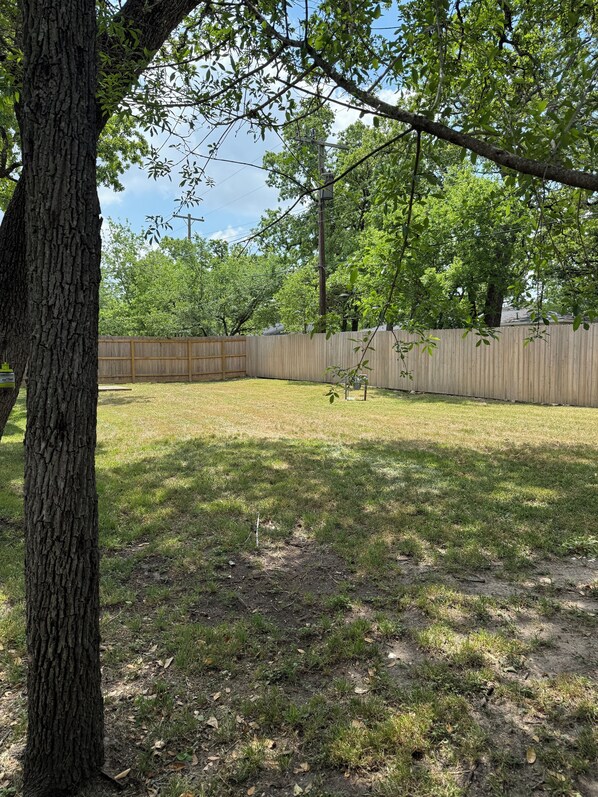 A backyard with a wooden fence, trees, and a grassy area. - Walking Distance to Campus 3/2, newly renovated and professionally decorated! (Bryan)