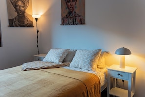 Cozy retreat with a neatly made bed, nightstand, and wall art.