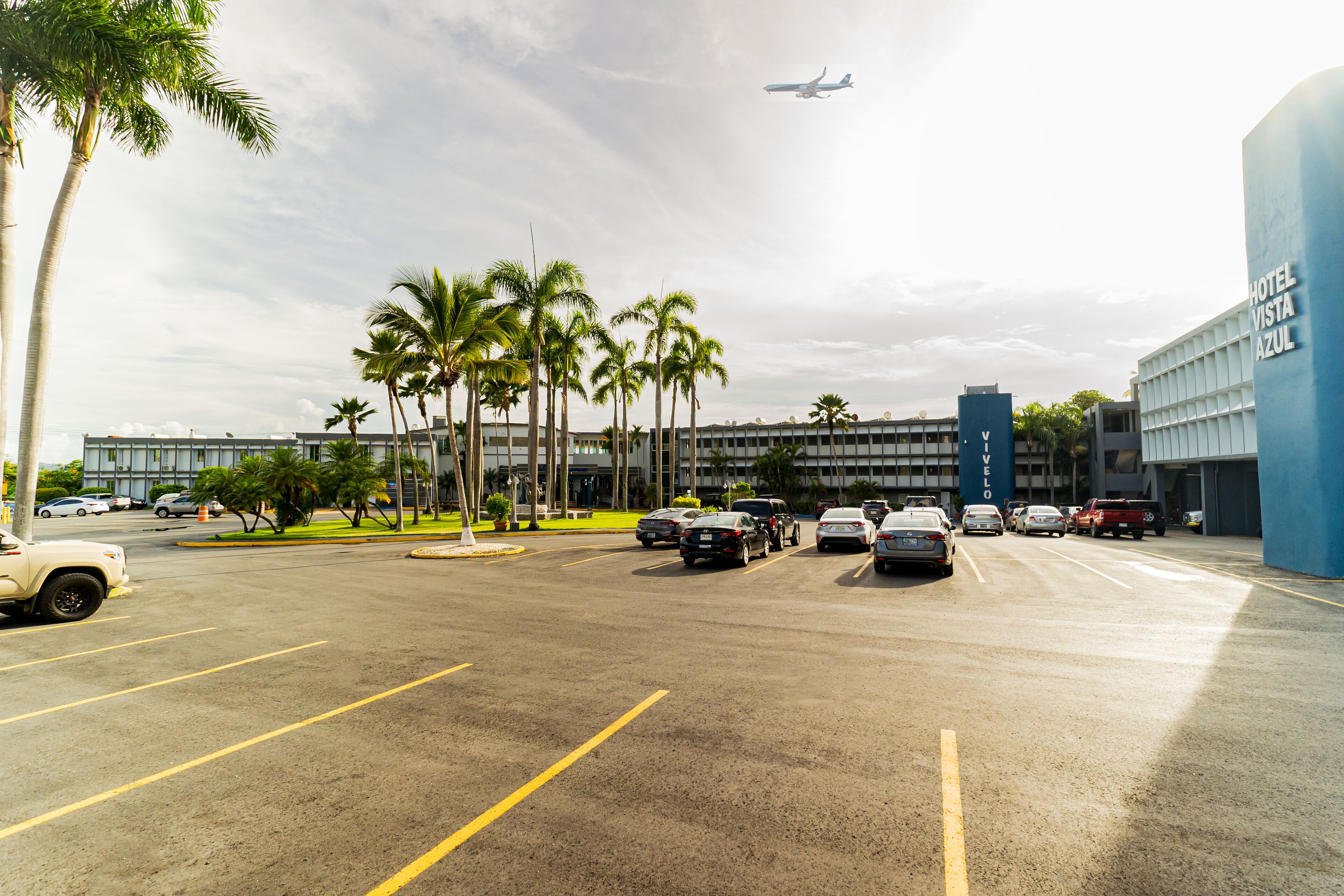A parking lot with cars, palm trees, and a building labeled "Hotel Vista Azul".
