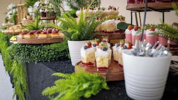 En buffé med olika sorters desserter och frukter, presenterade på träbrickor och i vita skålar.