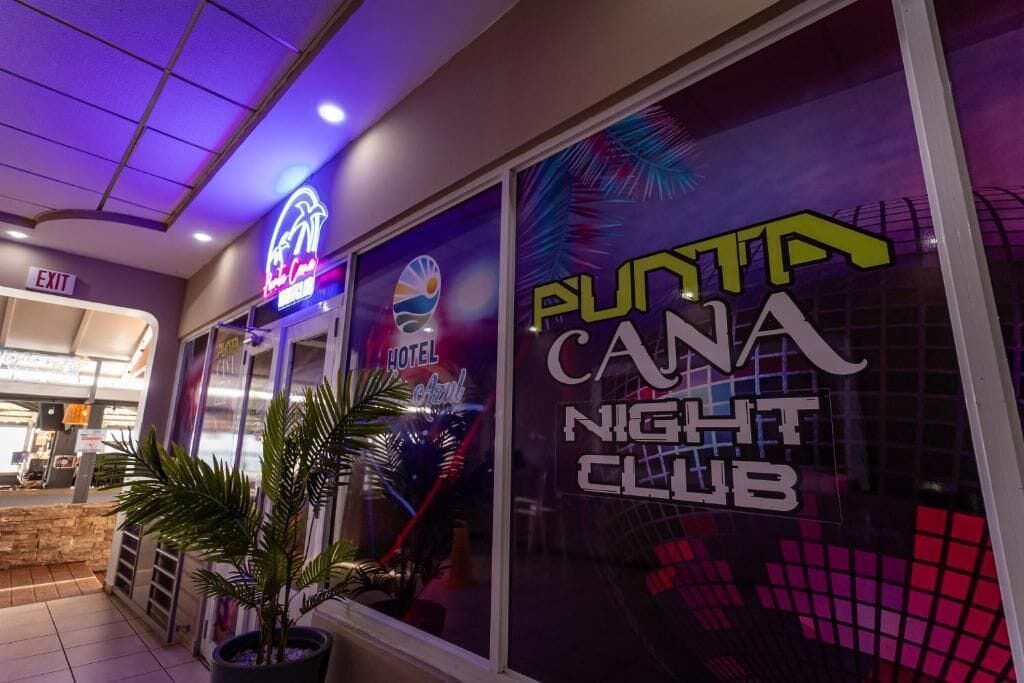 A hotel entrance with a neon sign and a large window displaying the name 'Punta Cana Night Club'.