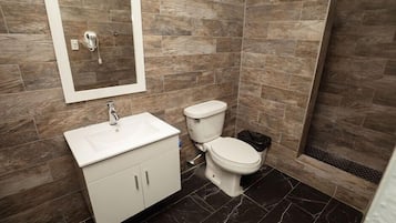 A bathroom with a white sink, toilet, and shower area.