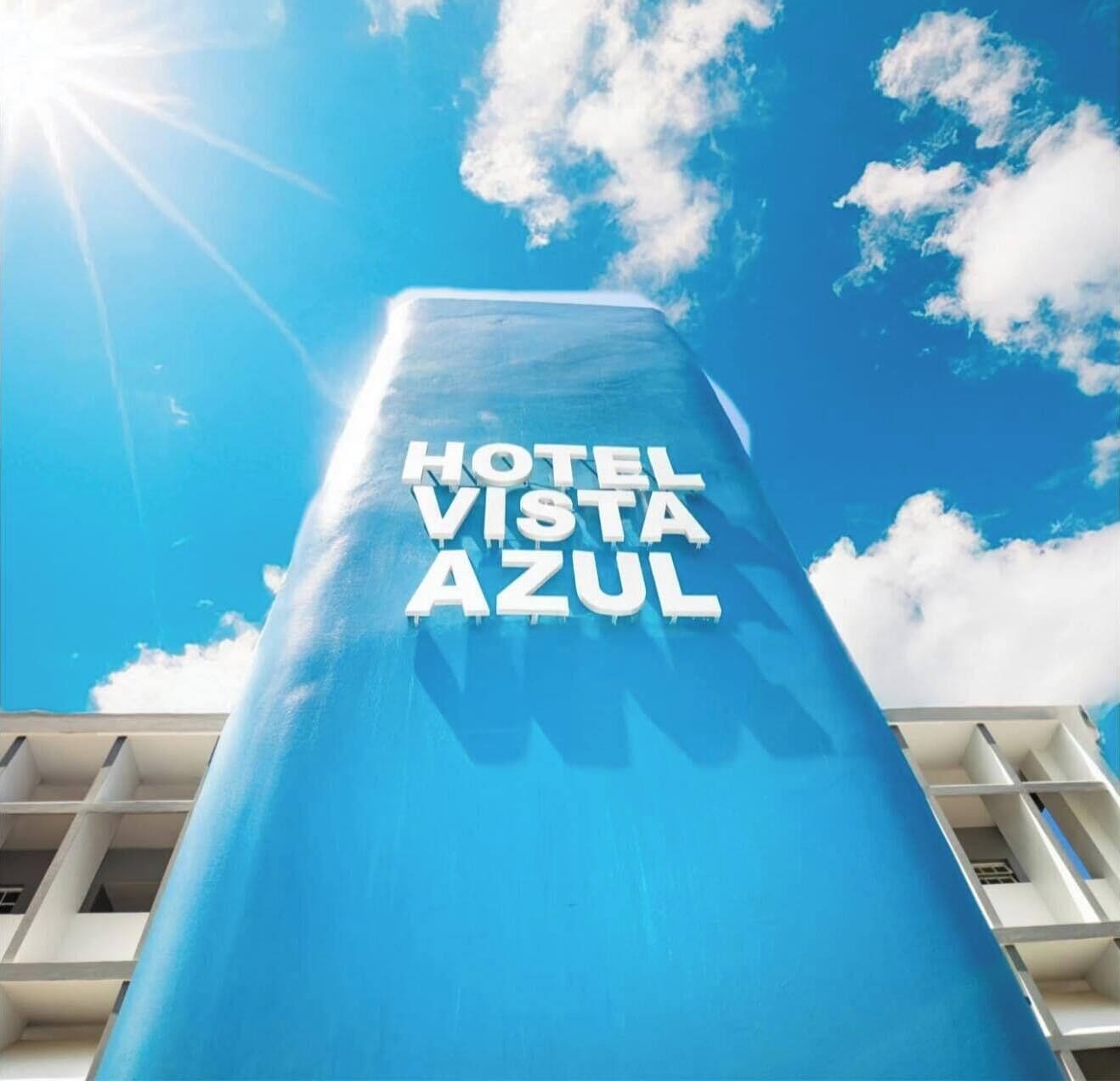Un moderno edificio de hotel con el nombre "HOTEL VISTA AZUL" visible en su fachada.