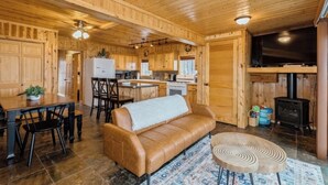 A wooden cabin interior with a kitchen, dining area, and living room.