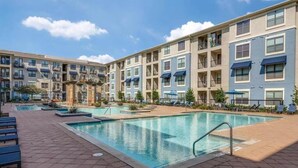 Un hôtel à plusieurs étages doté d’une piscine centrale, d’un espace extérieur aménagé pour s’asseoir et d’un jardin paysager.