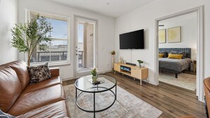 Un salon moderne avec un canapé en cuir, une table basse en verre et un téléviseur à écran plat fixé au mur.