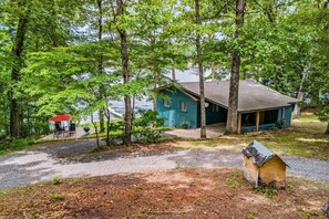 A house with a porch, surrounded by trees and a gravel path.