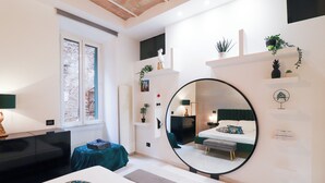 A modern bedroom with a large mirror, a bed, a desk, and shelves with plants. - Charming apartment with WiFi, closed to Colosseo and Santa Maria Maggiore. (Roma)
