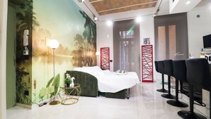 A room with a bed, a massage table, and a row of bar stools. - Charming apartment with WiFi, closed to Colosseo and Santa Maria Maggiore. (Roma)