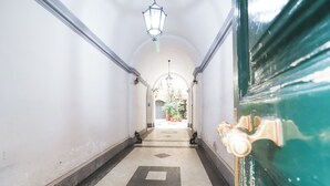 A hallway with a tiled floor, a green door with a brass handle, and a hanging light fixture. - Charming apartment with WiFi, closed to Colosseo and Santa Maria Maggiore. (Roma)