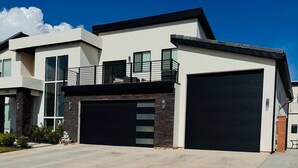 A modern two-story house with a large garage, a balcony, and a well-maintained front yard. - Charming 2-bedroom house Near Zion & Sand Hollow (HURRICANE)