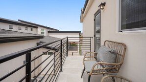 A balcony with a wicker chair and a small table, a railing, and a view of neighboring buildings. - Charming 2-bedroom house Near Zion & Sand Hollow (HURRICANE)