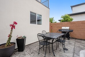A patio with a table and chairs, a grill, and potted plants. - Charming 2-bedroom house Near Zion & Sand Hollow (HURRICANE)