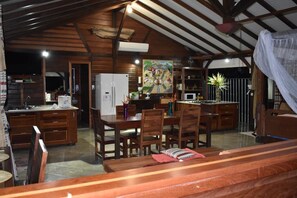 A spacious kitchen with wooden cabinets, a dining area with a table and chairs, and a large painting on the wall. - Habitation Bonneville Chalet & Loft swimming pool and sauna (La Trinité)